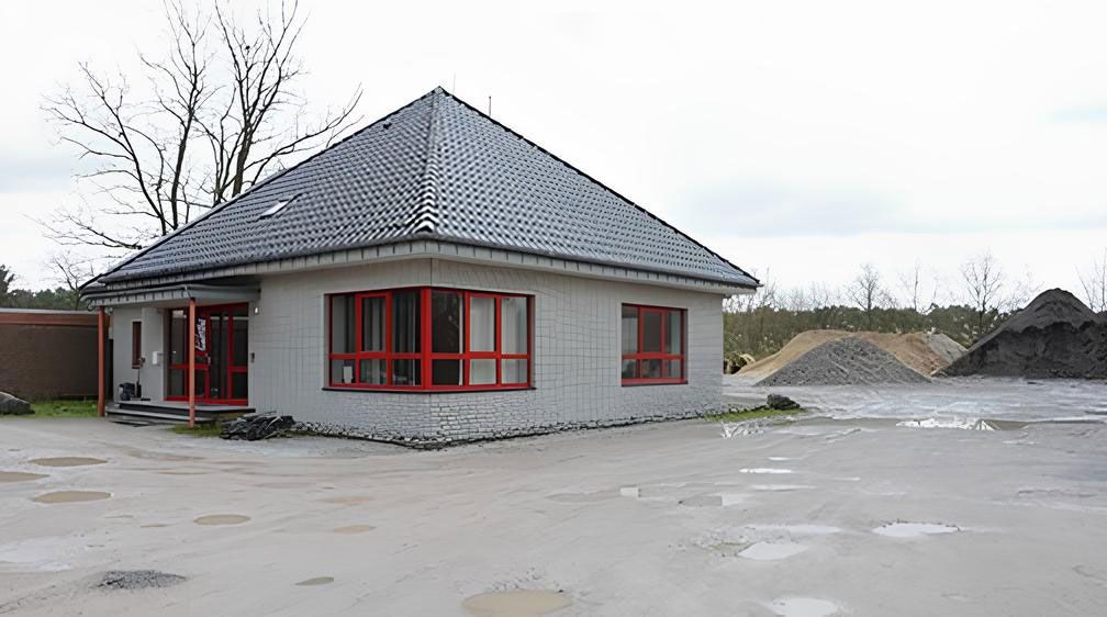 Graues Haus mit rot eingerahmter Fensterfront